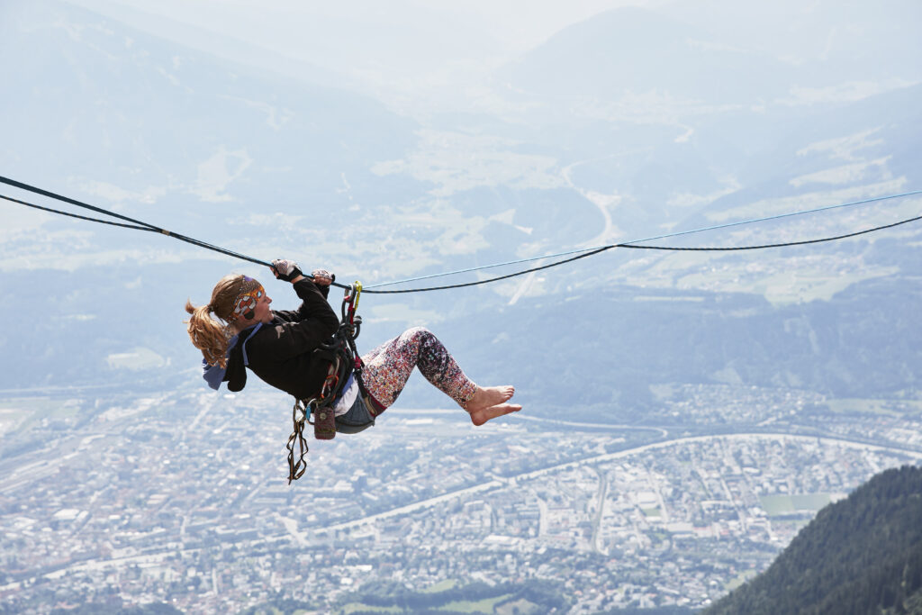 Adventurer ziplining over a scenic mountain town.